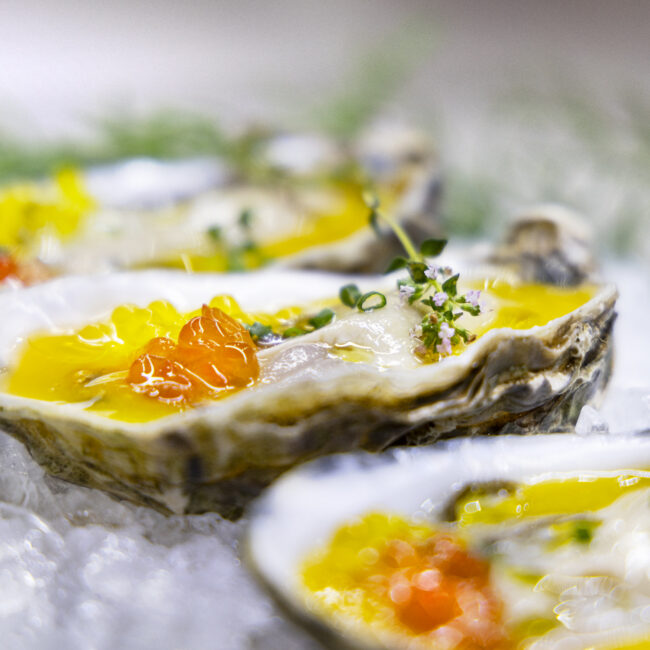 Ostras frescas sobre hielo con vinagreta y huevas en fotografía gastronómica profesional de marisco