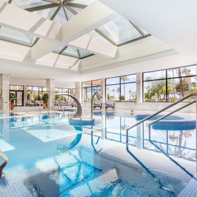 Piscina interior del hotel Hipotels con zona de spa y grandes ventanales